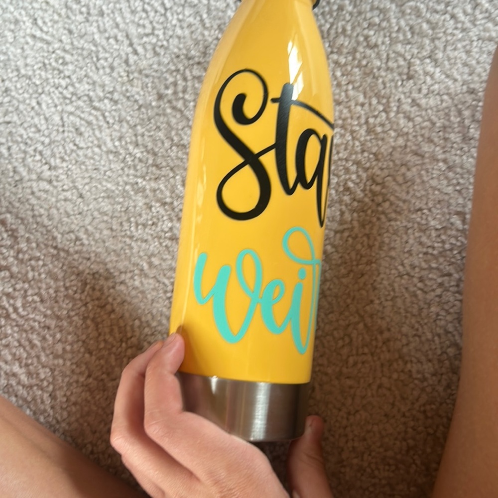 Yellow 22oz cup with black and blue lettering that says stay weird